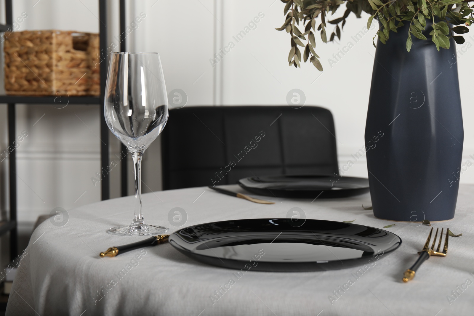 Photo of Stylish table setting with black dishware in dining room