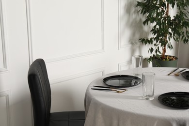 Photo of Stylish table setting with black dishware in dining room