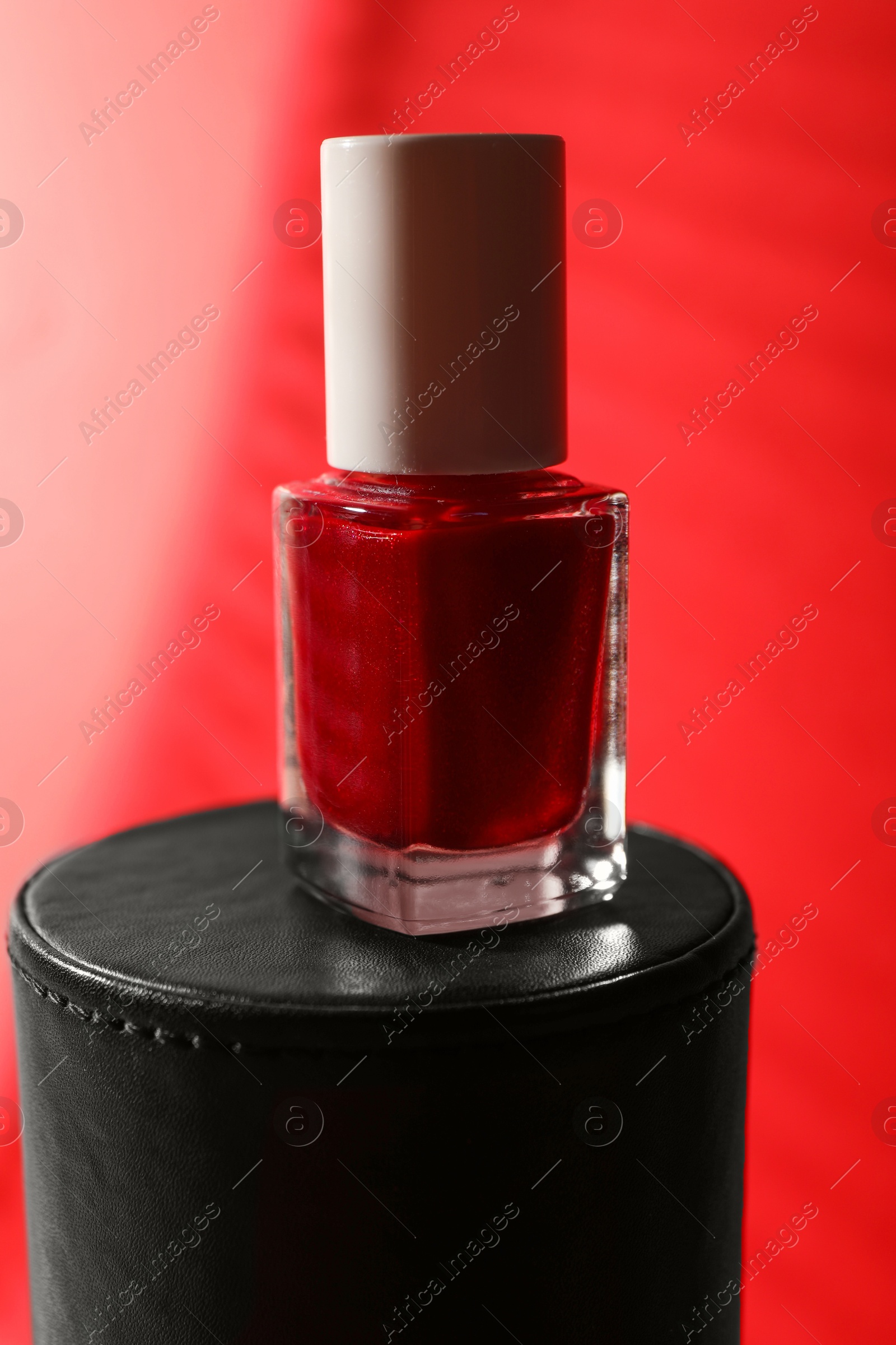 Photo of Nail polish in bottle on red background