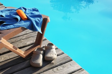 Photo of Beach accessories and sun lounger on wooden deck near outdoor swimming pool