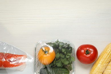 Photo of Different products with plastic food wrap on white wooden table, flat lay. Space for text