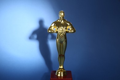 Photo of One golden Oscar award on blue background