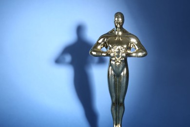 Photo of One golden Oscar award on blue background, space for text