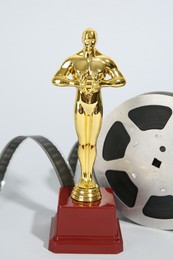 Golden Oscar award and film reel on light background