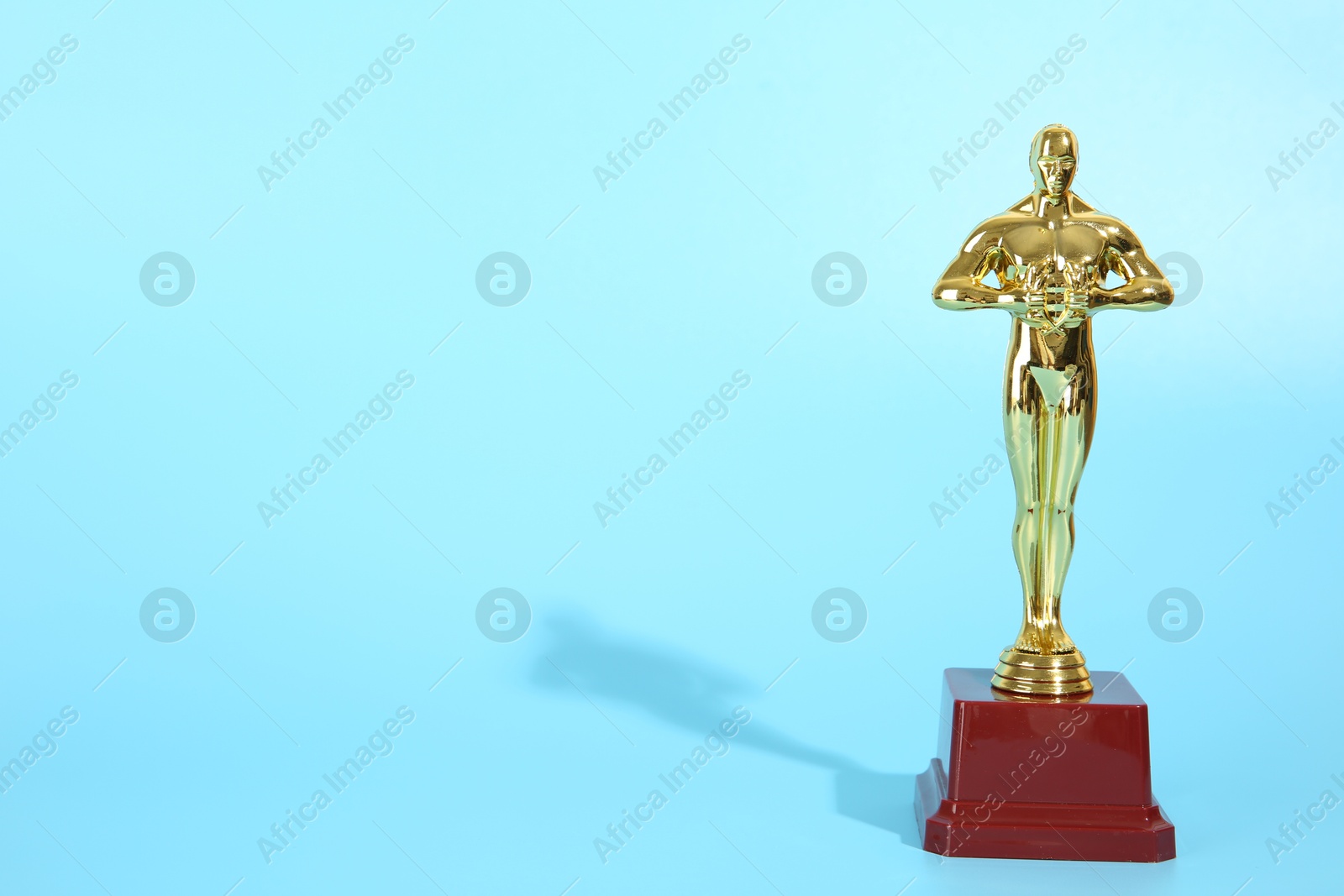 Photo of One golden Oscar award on light blue background, space for text