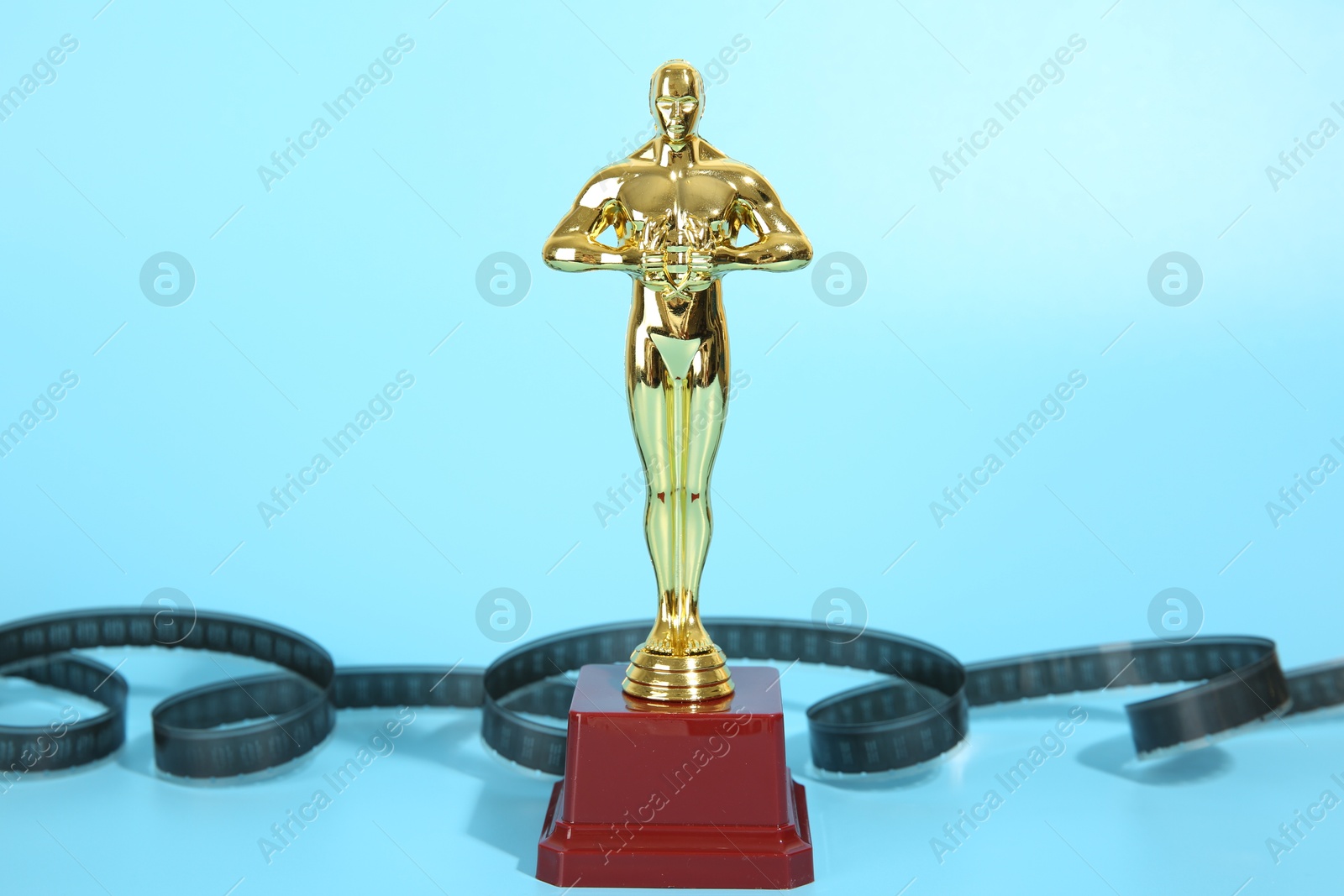 Photo of Golden Oscar award and film reel on light blue background