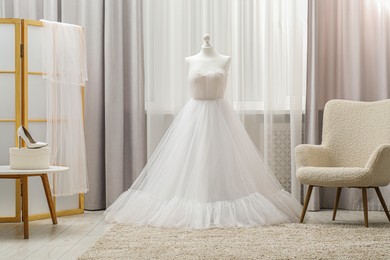 Photo of Beautiful wedding dress on mannequin and shoes in boutique