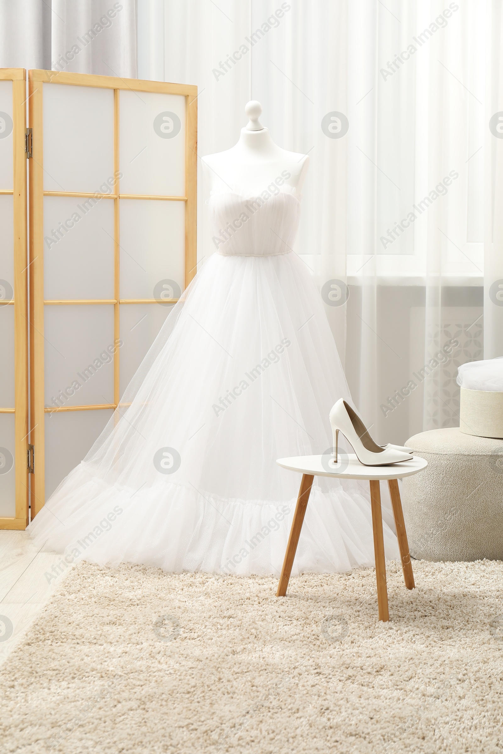 Photo of Beautiful wedding dress on mannequin and shoes in boutique