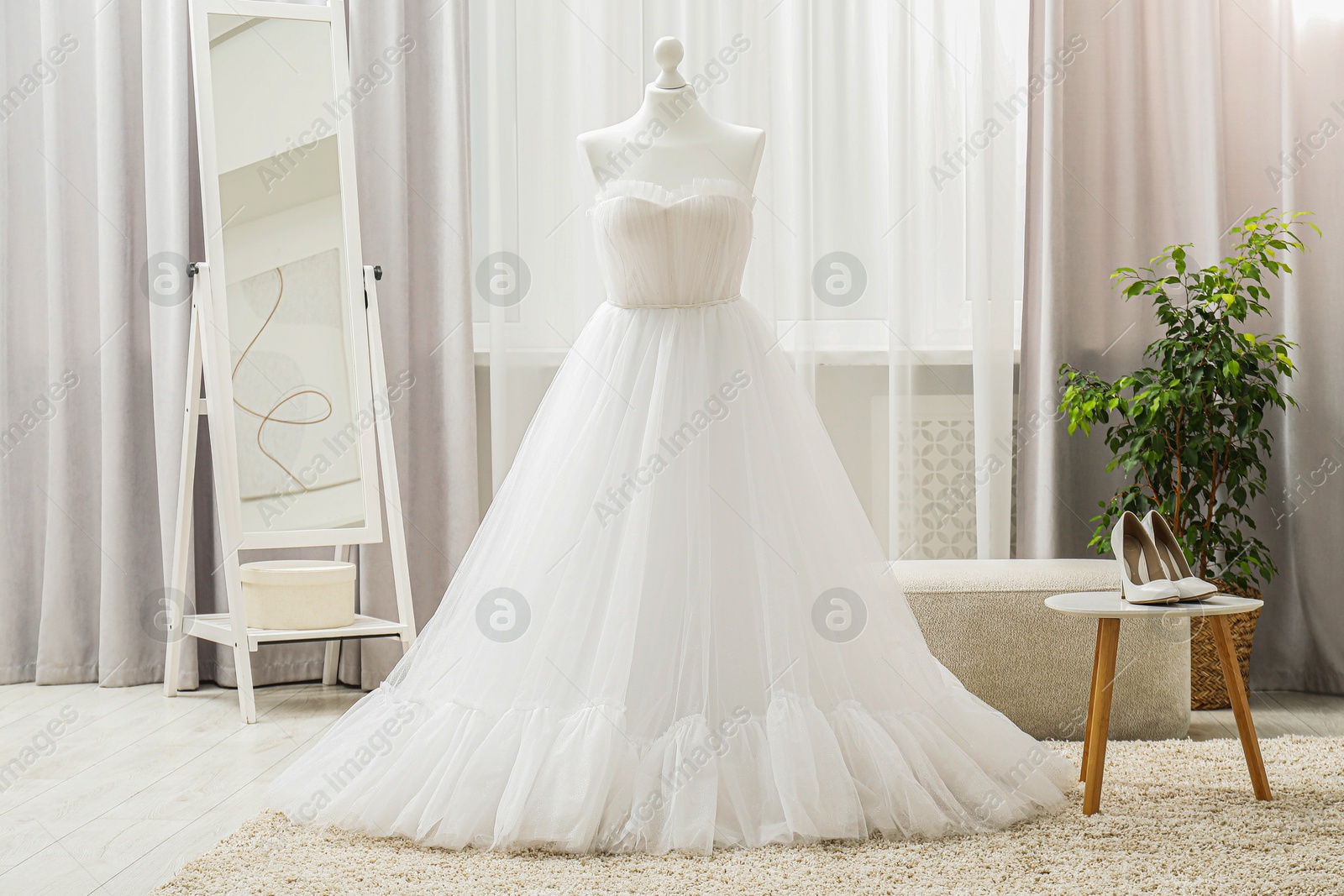 Photo of Beautiful wedding dress on mannequin and shoes in boutique