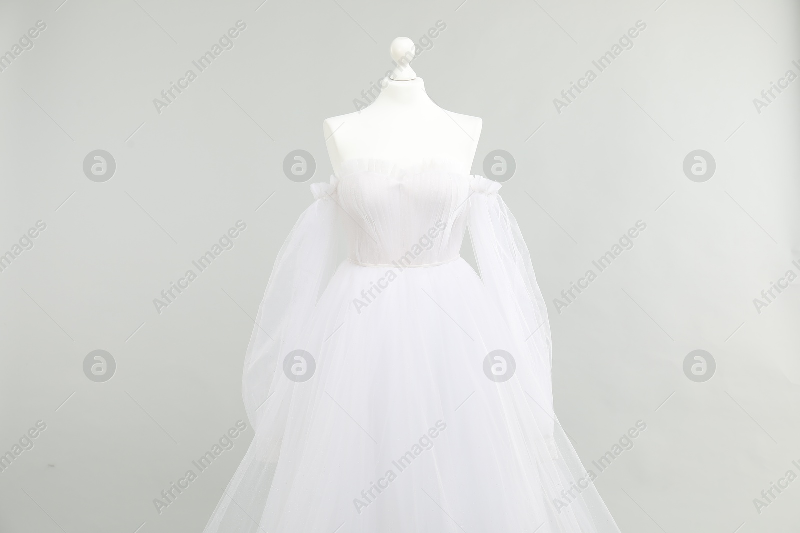 Photo of Mannequin with beautiful wedding dress on light grey background