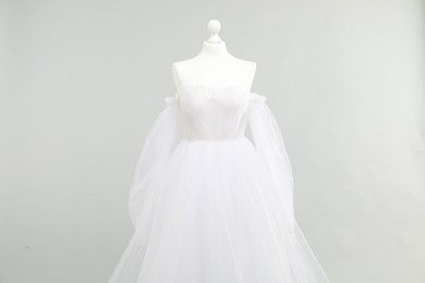 Photo of Mannequin with beautiful wedding dress on light grey background