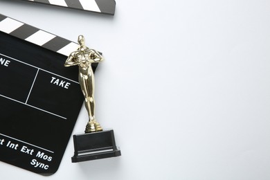 Photo of Golden Oscar award and movie clapper on white background, top view. Space for text