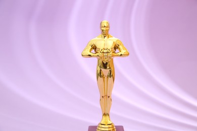 Photo of One golden Oscar award on violet background