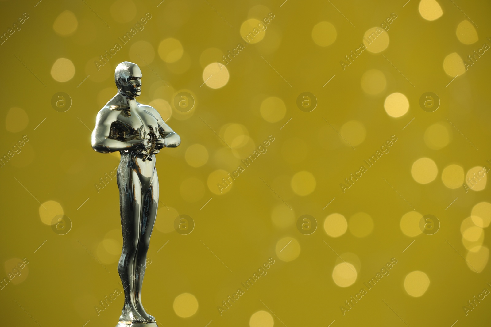 Photo of Golden Oscar award on olive background with blurred lights, space for text