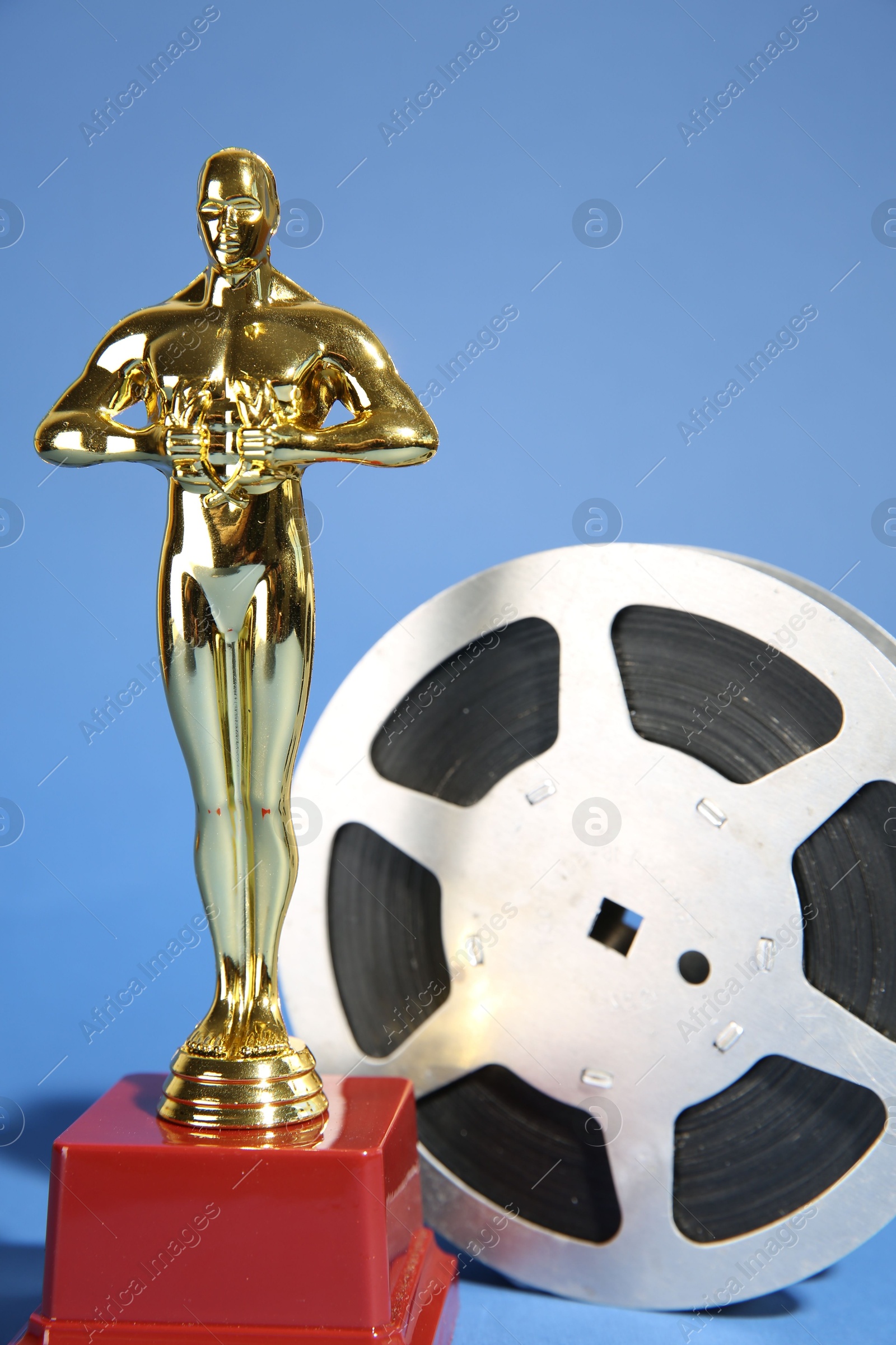 Photo of Golden Oscar award and film reel on light blue background