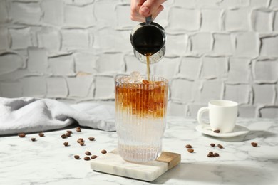 Woman making refreshing espresso tonic drink at white marble table, closeup