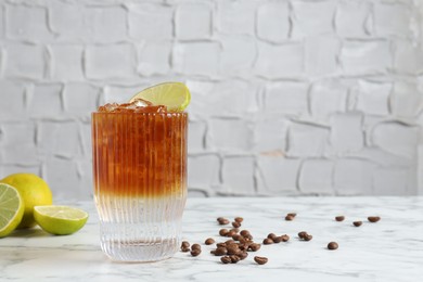 Photo of Refreshing espresso tonic drink with lime and coffee beans on white marble table. Space for text