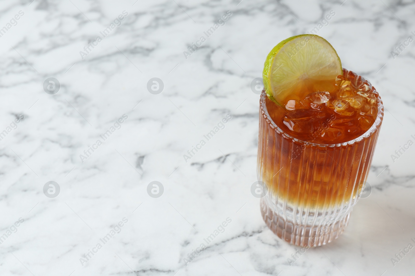 Photo of Refreshing espresso tonic drink with slice of lime on white marble table, closeup. Space for text