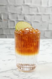 Refreshing espresso tonic drink with slice of lime on white marble table