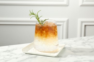 Photo of Refreshing espresso tonic drink with rosemary on white marble table