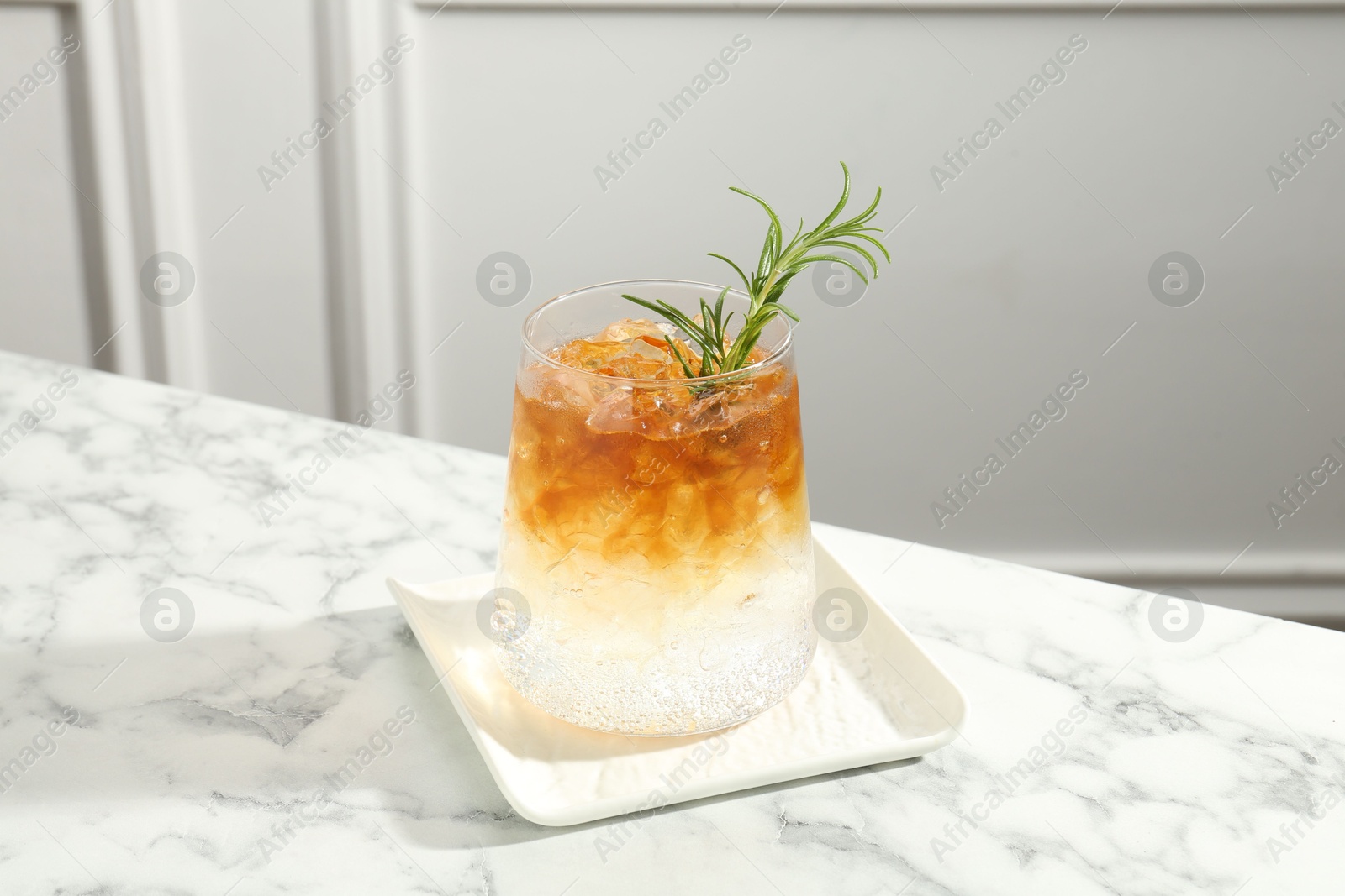 Photo of Refreshing espresso tonic drink with rosemary on white marble table