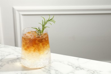 Photo of Refreshing espresso tonic drink with rosemary on white marble table, space for text