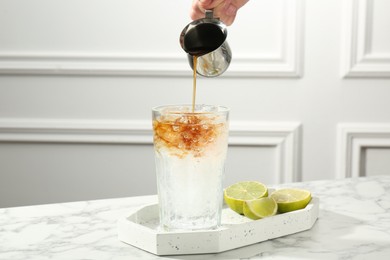 Woman making refreshing espresso tonic drink at white marble table, closeup