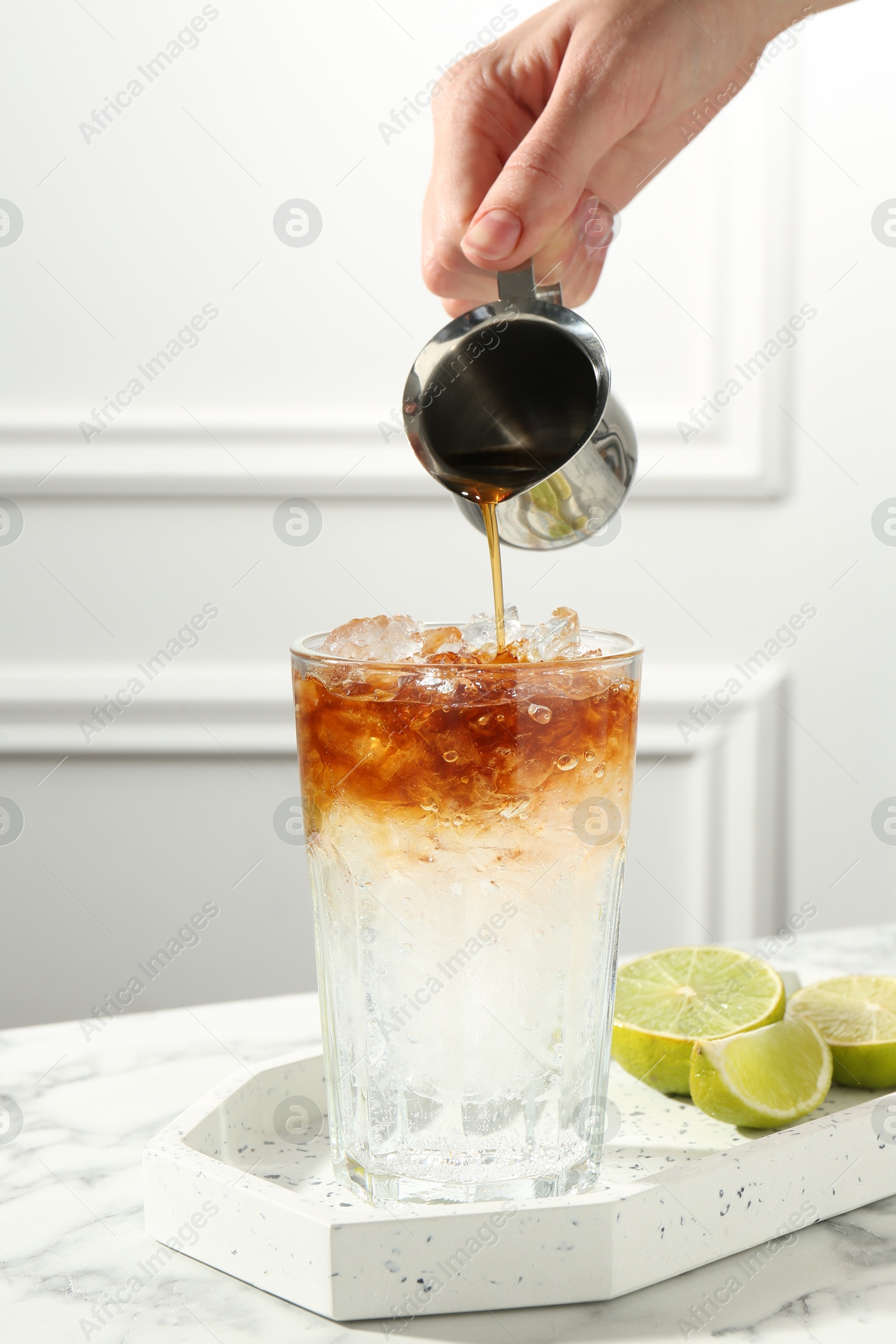 Photo of Woman making refreshing espresso tonic drink at white marble table, closeup