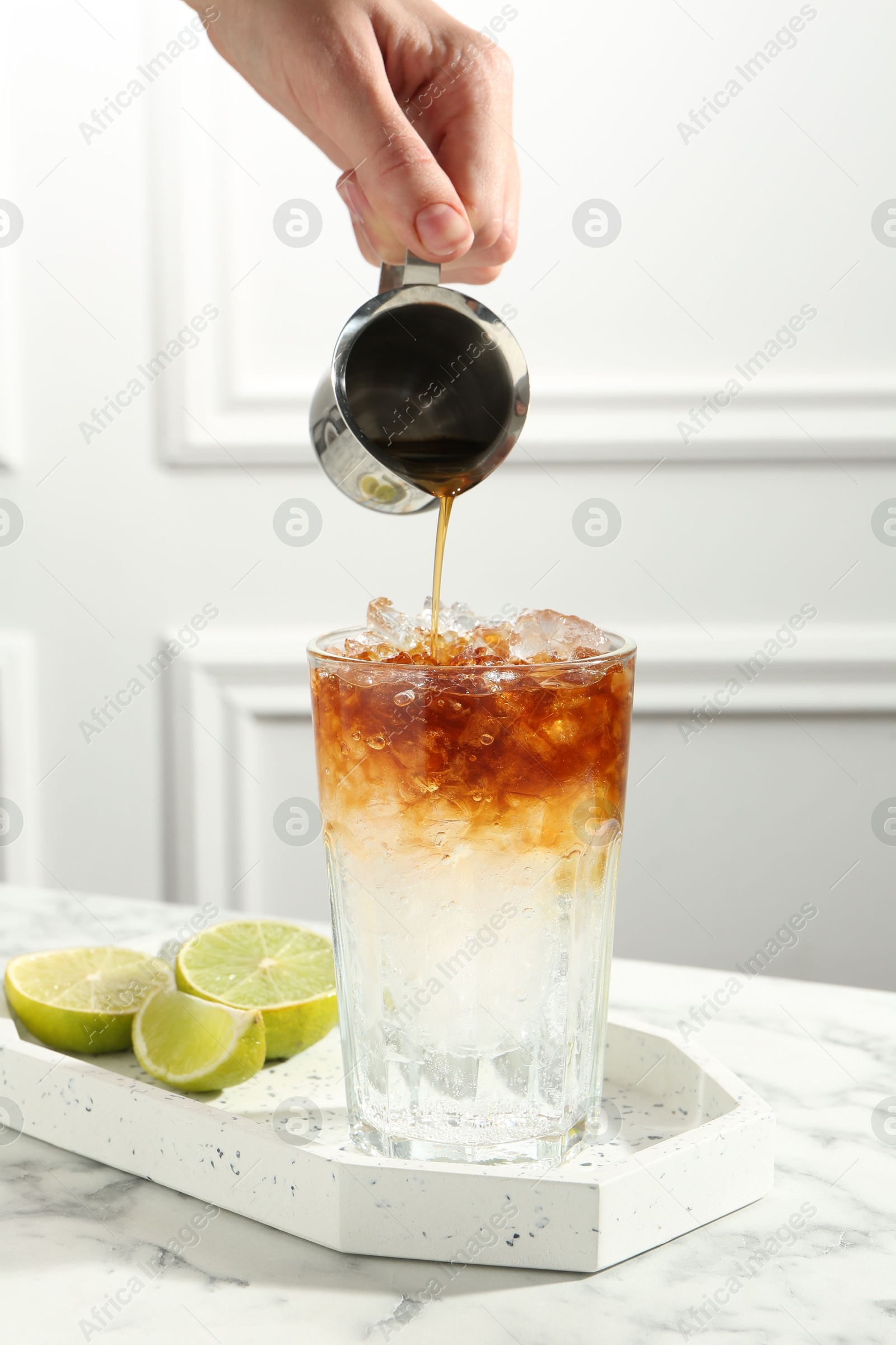 Photo of Woman making refreshing espresso tonic drink at white marble table, closeup