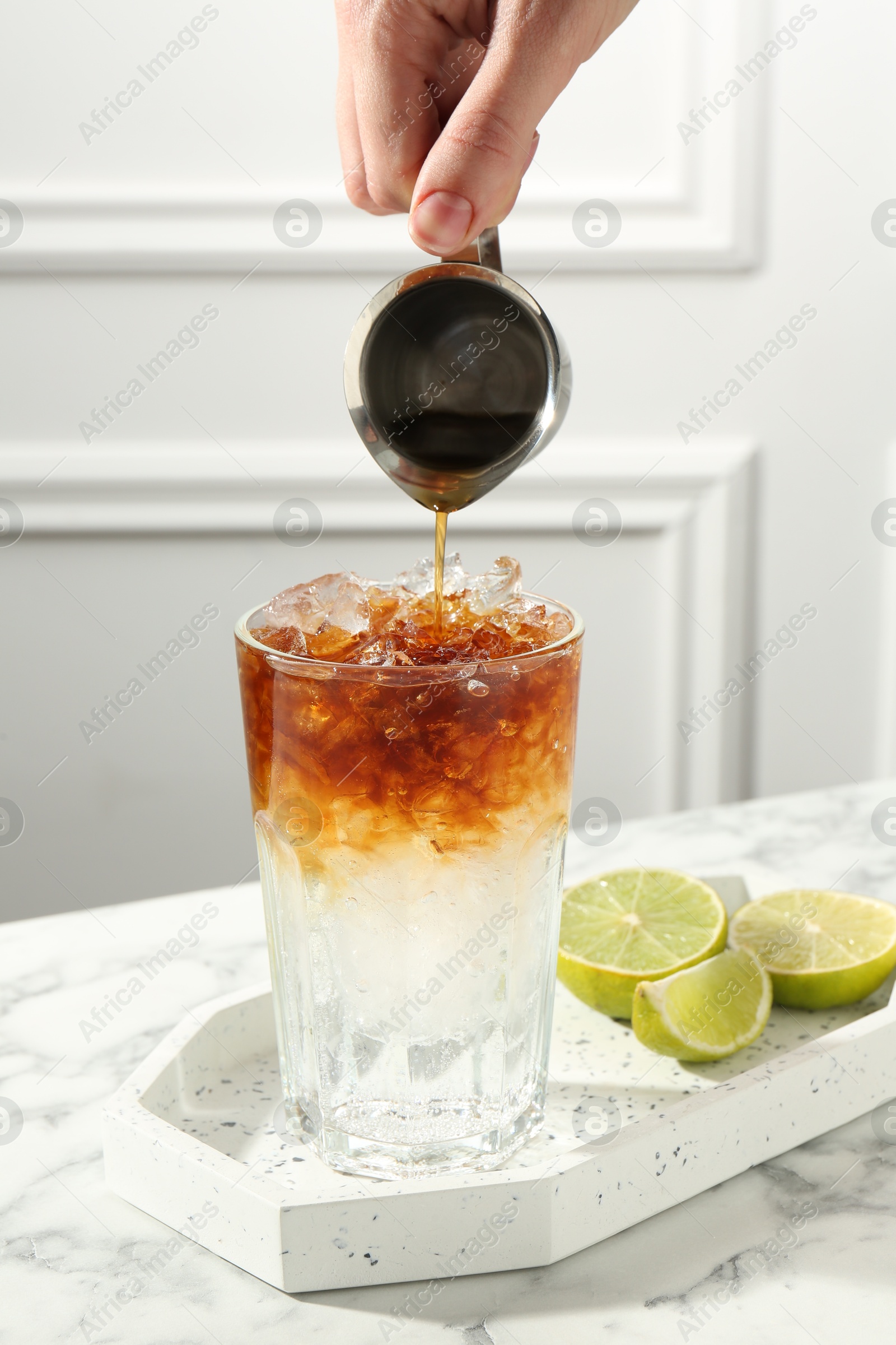 Photo of Woman making refreshing espresso tonic drink at white marble table, closeup