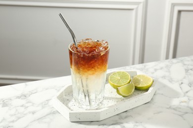 Photo of Refreshing espresso tonic drink and lime on white marble table