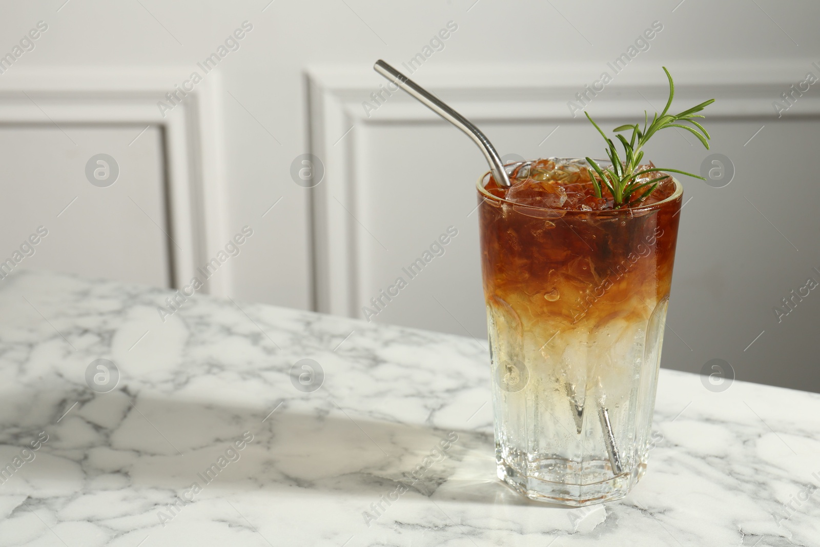 Photo of Refreshing espresso tonic drink with rosemary on white marble table, space for text