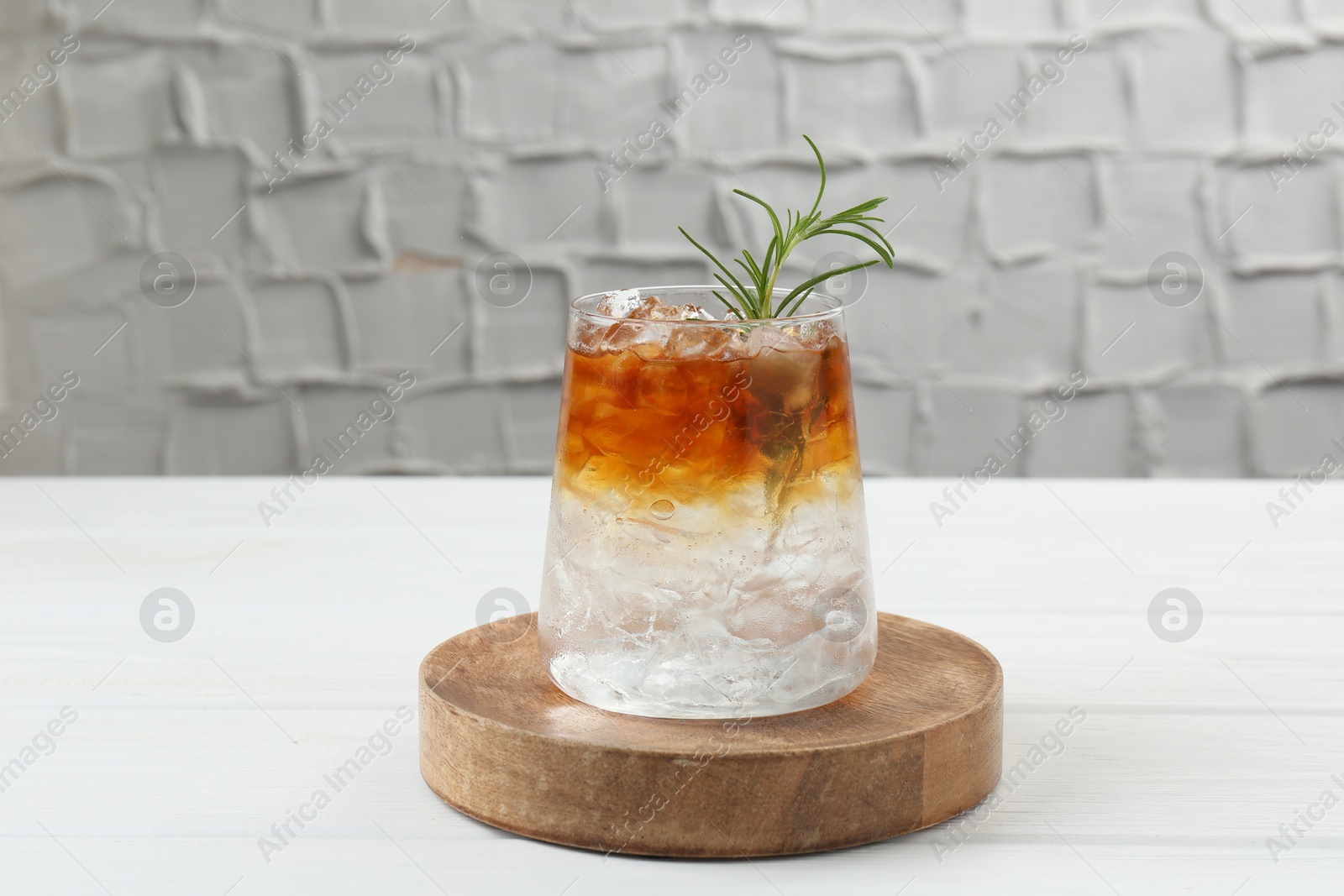 Photo of Refreshing espresso tonic drink with rosemary on white wooden table