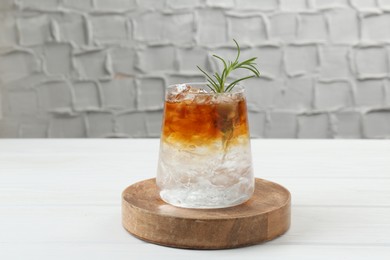 Refreshing espresso tonic drink with rosemary on white wooden table