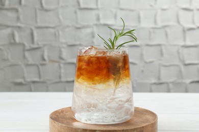 Photo of Refreshing espresso tonic drink with rosemary on white table