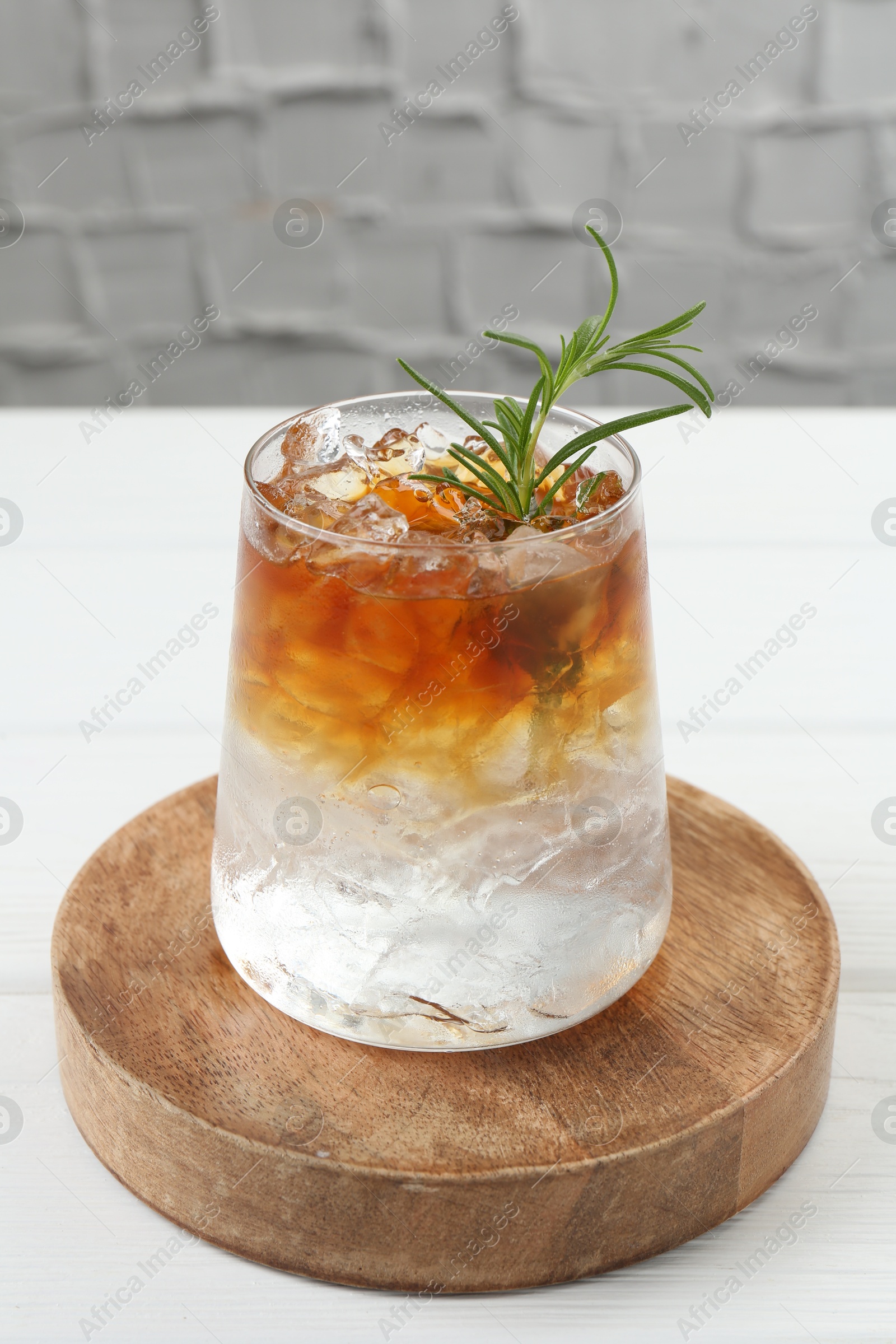 Photo of Refreshing espresso tonic drink with rosemary on white table, closeup