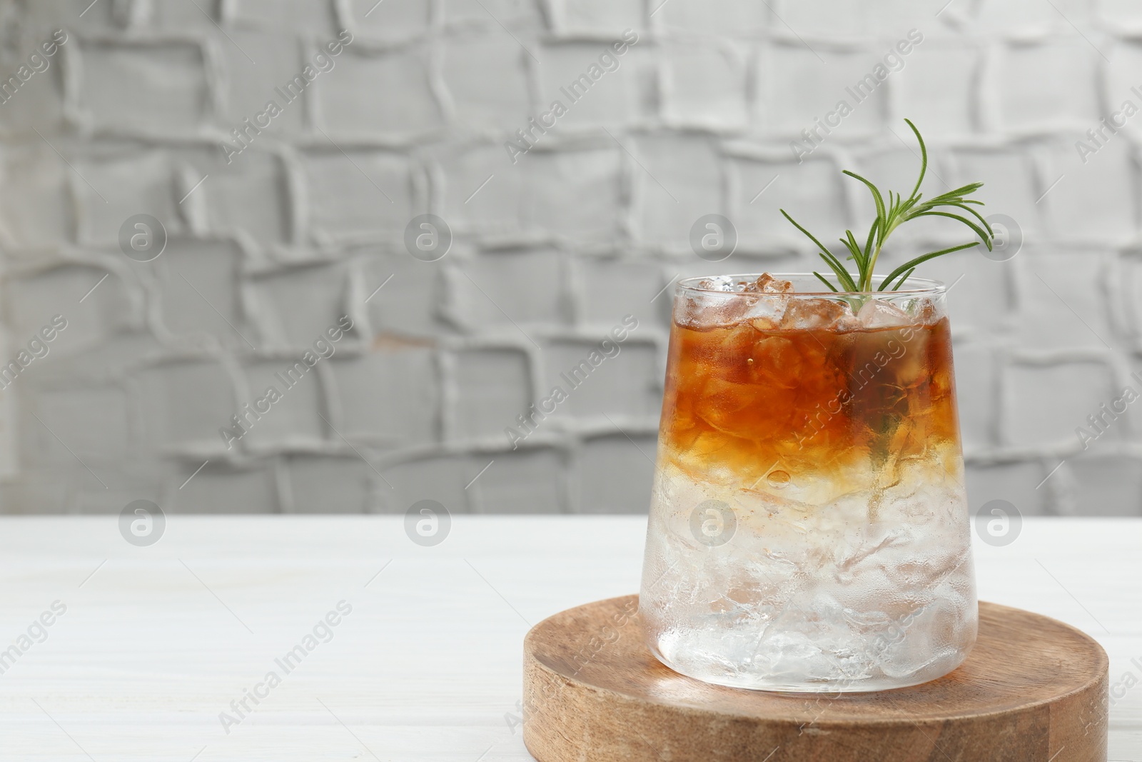 Photo of Refreshing espresso tonic drink with rosemary on white table, space for text