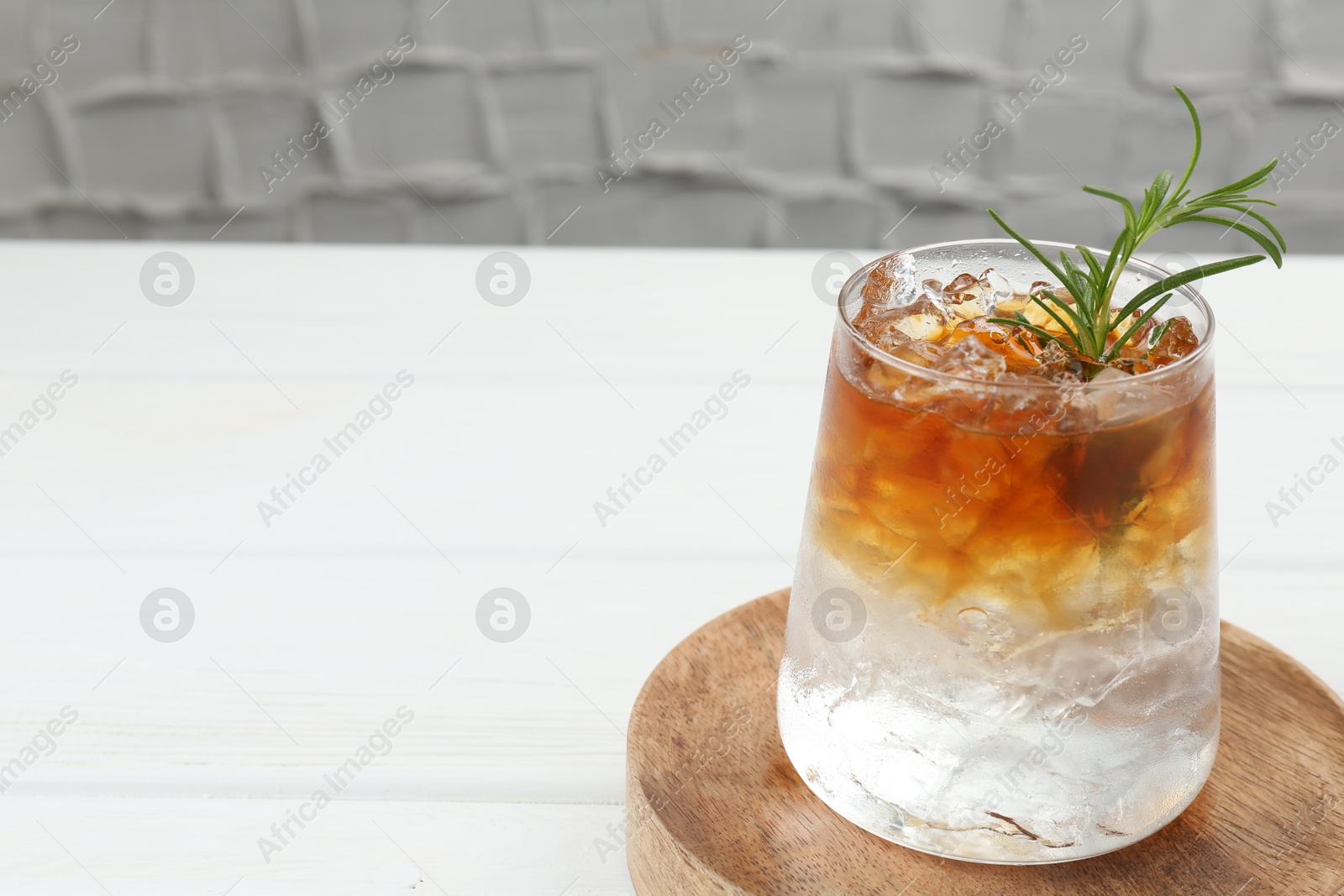 Photo of Refreshing espresso tonic drink with rosemary on white wooden table, closeup. Space for text