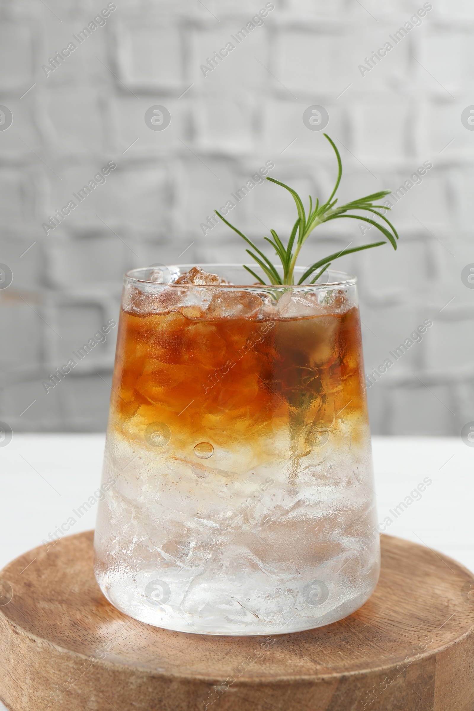 Photo of Refreshing espresso tonic drink with rosemary on table, closeup