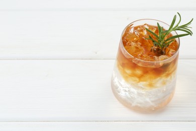 Photo of Refreshing espresso tonic drink with rosemary on white wooden table, closeup. Space for text