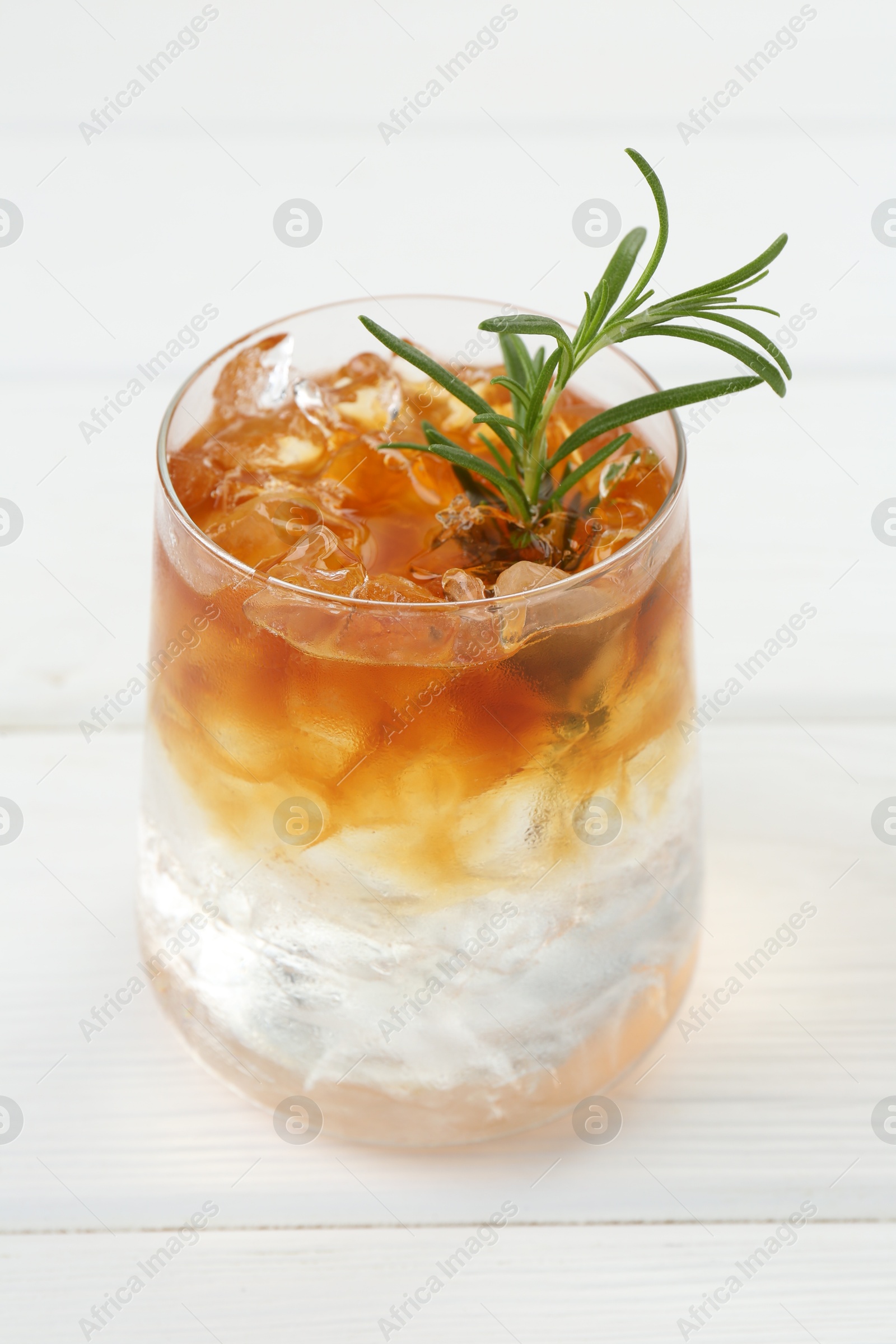 Photo of Refreshing espresso tonic drink with rosemary on white wooden table, closeup