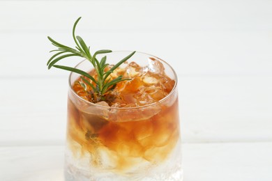 Refreshing espresso tonic drink with rosemary on white table, closeup