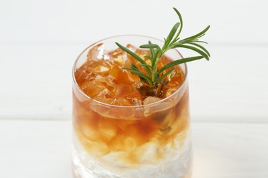 Refreshing espresso tonic drink with rosemary on white table, closeup