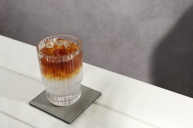 Photo of Refreshing espresso tonic drink on white wooden table, space for text