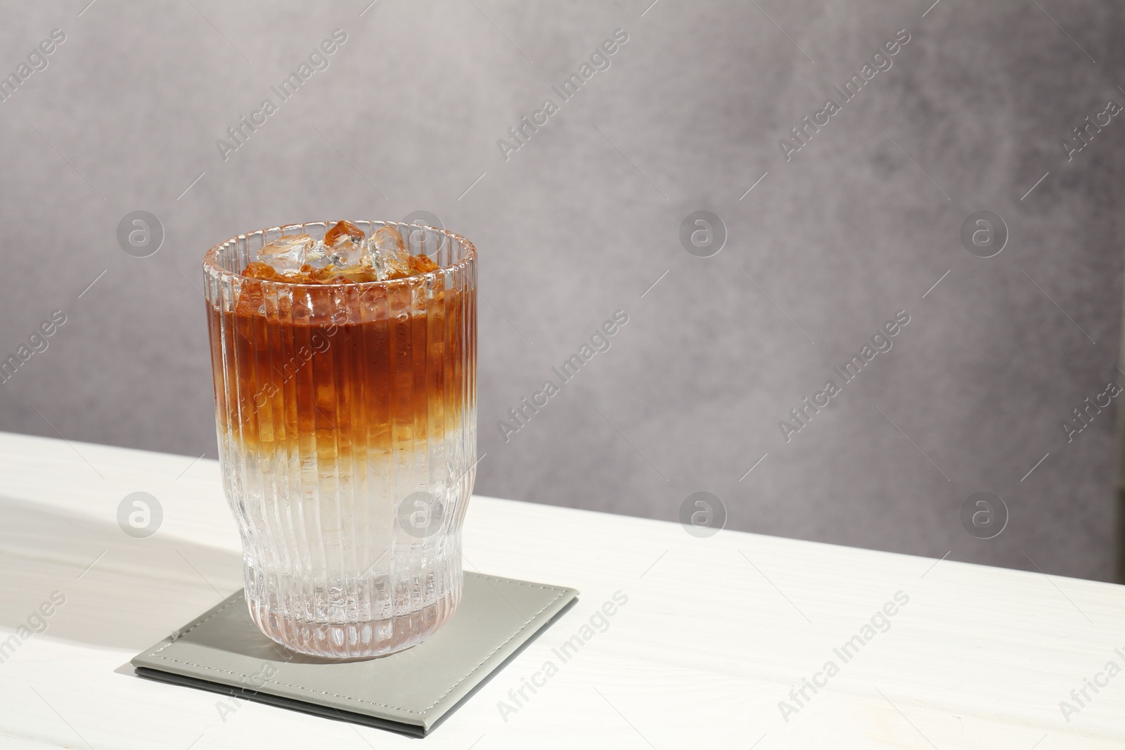 Photo of Refreshing espresso tonic drink on white wooden table, space for text