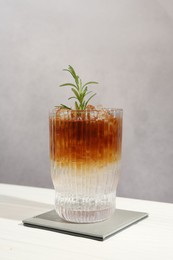 Refreshing espresso tonic drink with rosemary on white table