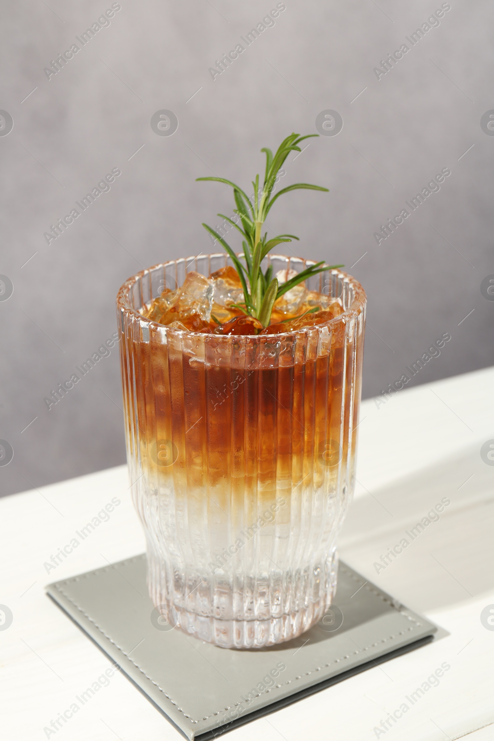 Photo of Refreshing espresso tonic drink with rosemary on white table