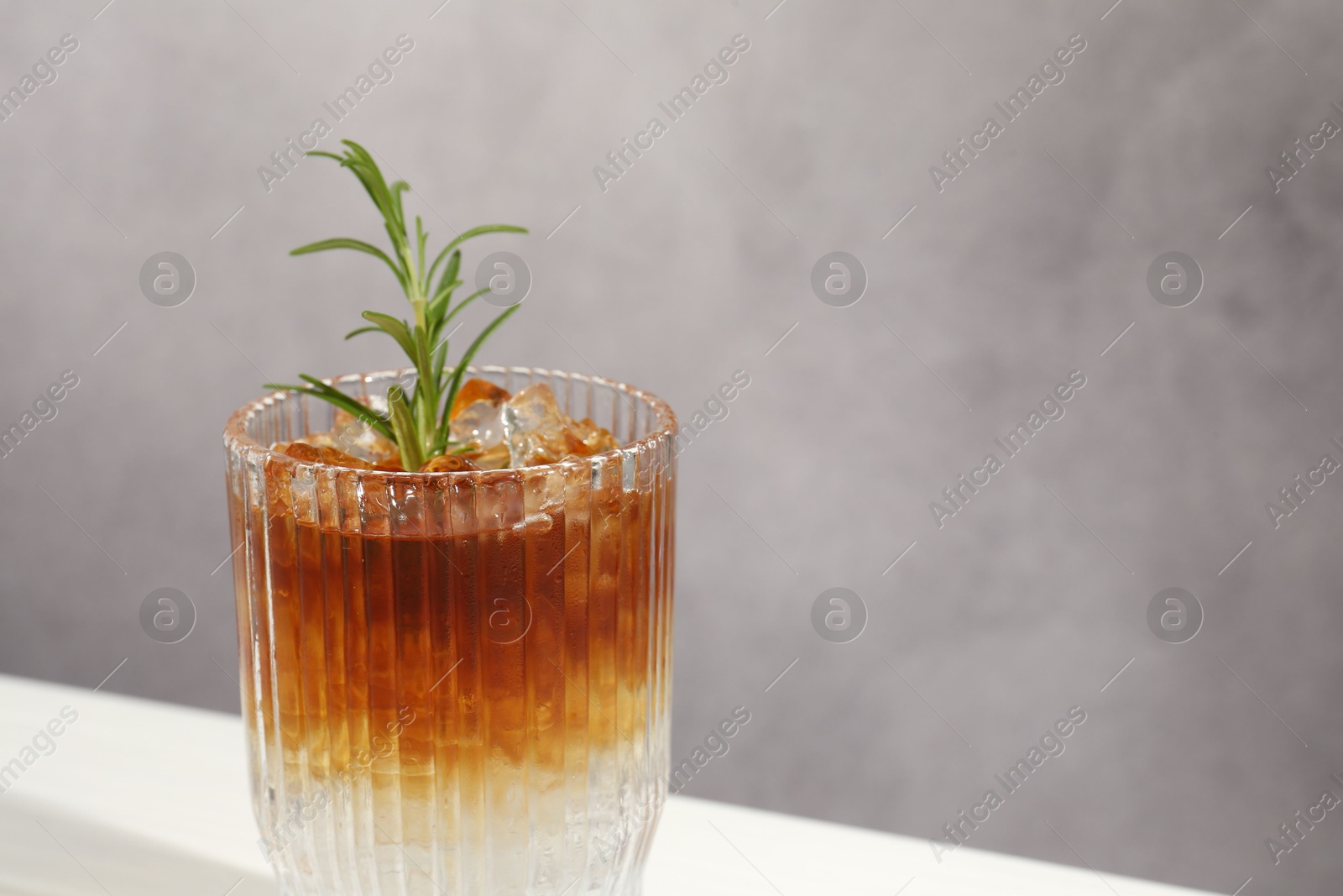 Photo of Refreshing espresso tonic drink with rosemary on table, closeup. Space for text