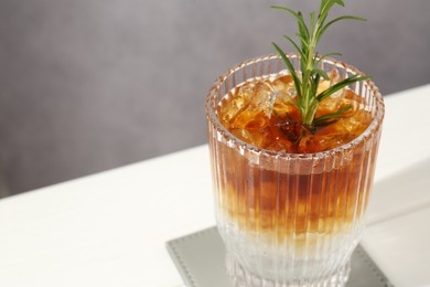 Photo of Refreshing espresso tonic drink with rosemary on white table, closeup. Space for text