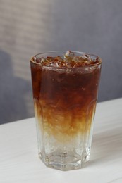 Refreshing espresso tonic drink on white wooden table